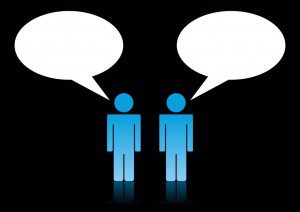 Two people engaging in conversation with speech bubbles on a black background, emphasizing the need for more communication.