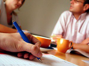 A person is taking notes on a piece of paper in preparation for meetings.