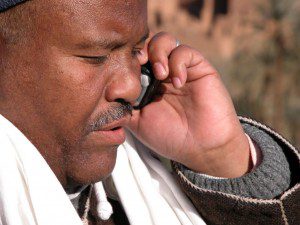 A man urgently talking on a cell phone, trying to shut up and listen.