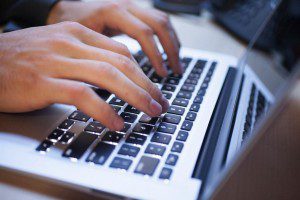 A person typing emails on a laptop keyboard.