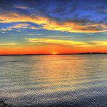 A majestic sunset serenely illuminating a vast water expanse, inspiring strength and resilience.