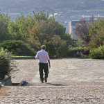 A man pondering his choices walks down a cobblestone path.