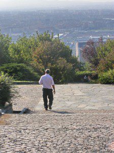 A man pondering his choices walks down a cobblestone path.