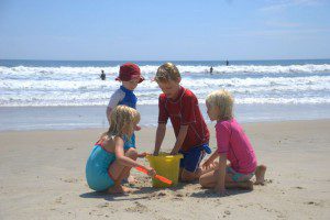 Four children playing and talking in the sand on the beach.