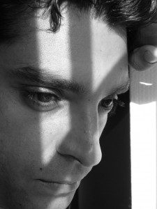 A man leaning against a wall in a black and white photo, defying labels.