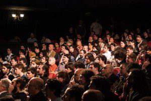 A crowd of introverted people watching a movie in an auditorium.