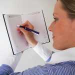 A woman making time to plan, diligently writing in a notebook.