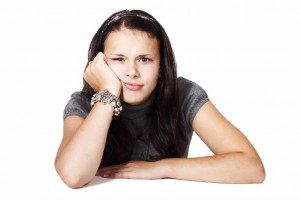 A contemplative young woman pauses with her hand on her chin, reflecting upon the meaning of introversion.