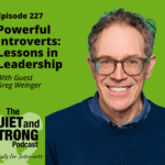 A man with glasses and a blue sweater smiles in front of a green background with text promoting Episode 227 of The Quiet and Strong Podcast about introvert leadership featuring Greg Weinger.