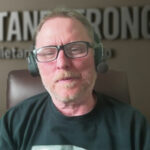 A middle-aged man with glasses and a headset sits in a chair, with the blurred text "QUIET AND STRONG" on the wall behind him, embodying introvert strengths and quiet success like David Hall.
